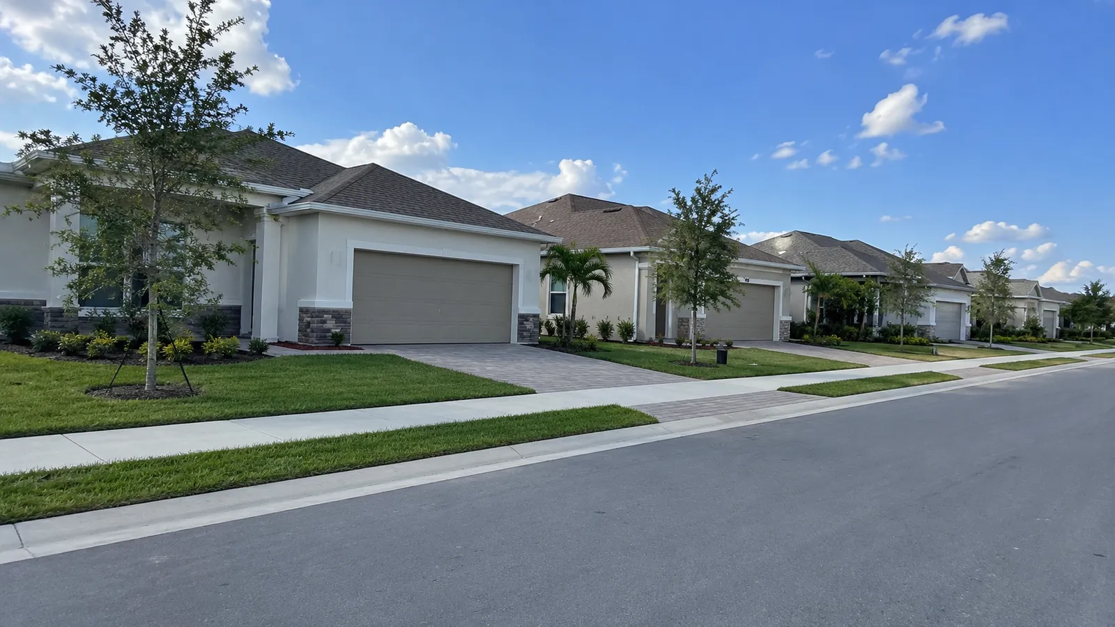 Row of newly built one-story stucco homes on a quiet street in a Florida subdivision